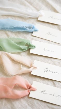 four ribbons with name tags on them sitting on a bed sheet, one for the bride and one for the groom