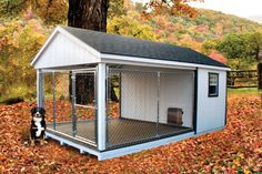 a small dog house in the middle of leaves with a black and white dog sitting next to it