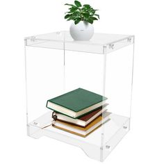 a stack of books sitting on top of a glass shelf next to a potted plant