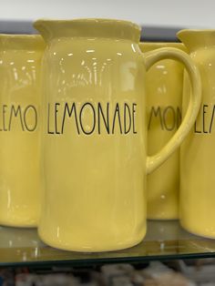 three yellow lemonade pitchers with the words lemonade written on them