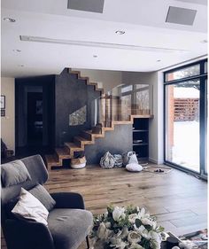 a living room filled with furniture and lots of windows next to a stair case in front of a sliding glass door