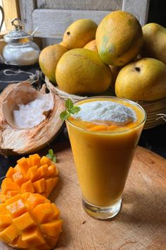 there is a glass of orange juice next to some mangos and other fruit on the table