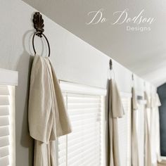 some towels hanging on the wall in front of white shutters and windows with drapes