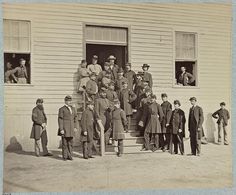 an old black and white photo of men in uniforms standing outside a building with their arms around each other