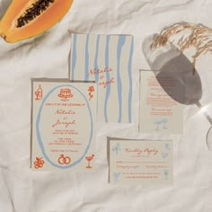 the wedding stationery is laid out on top of the table with fruit and paper