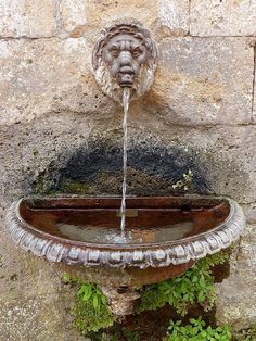 a water fountain with a lion head on it's face is shown in front of a stone wall