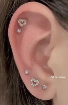 an ear with three heart shaped diamond studs on the top and bottom of it