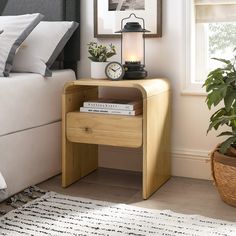 a bedroom with a bed, nightstand and clock on it's side table in front of a window