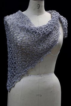 a white mannequin wearing a gray shawl on top of a dress form