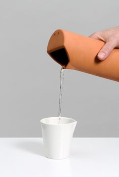 a person is pouring water into a cup