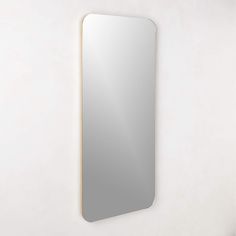 a mirror mounted on the wall above a sink in a room with white walls and flooring