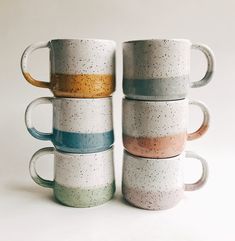 five coffee mugs stacked on top of each other in different colors and sizes with speckles