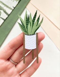 a hand holding a paper plant in a pot