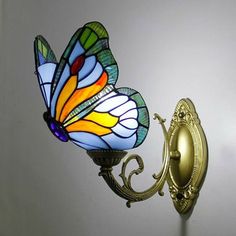 a colorful butterfly is on top of a wall light