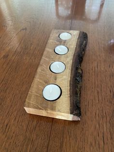 three white candles are placed on a piece of wood that is sitting on the floor