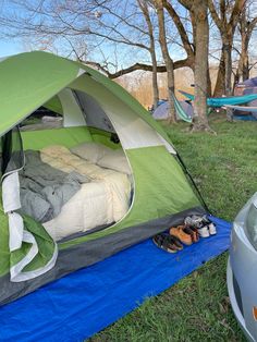 a tent is set up in the grass next to a car