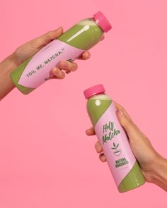 two hands holding green and pink juice bottles against a pink background that says, you're my matcha