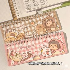 two notebooks with stickers on them sitting next to an open planner and pen