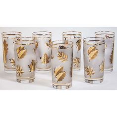 six glass tumblers with gold leaf designs on the outside and inside, all lined up against one another