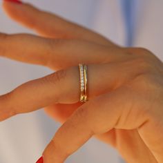 a woman's hand wearing a gold ring with three small diamonds on the band