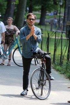 a man standing next to a bike with his hands folded in front of the camera