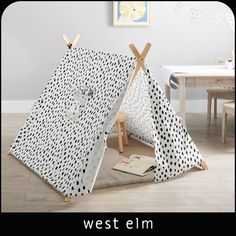 a child's teepee with black and white polka dot print on it, sitting in the middle of a room