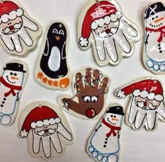 handprinted christmas ornaments are displayed on a white tablecloth with snowmen, penguins and santa hats