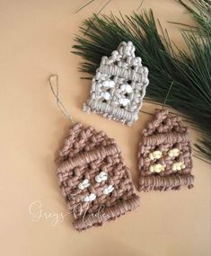 two crocheted mittens hanging from a pine tree with white balls on them