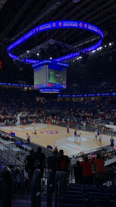 a basketball game is being played in an indoor arena with people watching from the stands