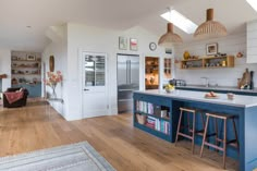 a kitchen with an island and blue cabinets in the center is surrounded by wood flooring