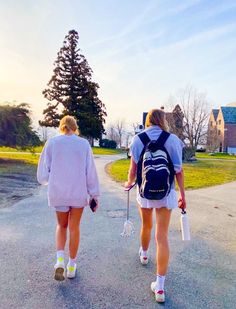 two women walking down the road with backpacks on