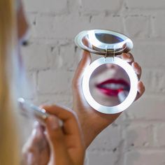 a woman is looking at her cell phone while holding a mirror in front of her face