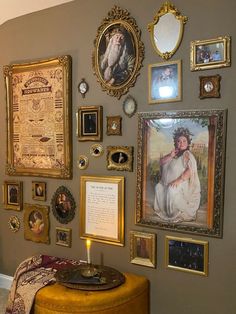 a wall with many framed pictures on it and a small table in front of it