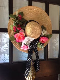 a straw hat with flowers on it hanging from a hook in front of a window