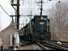 a train is traveling down the tracks near some power lines and trees with no leaves on them