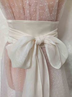 the back of a dress with white polka dots on it and a bow at the waist