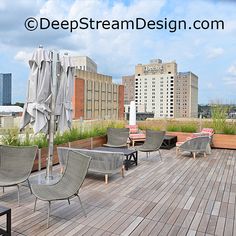 there are many chairs and umbrellas on the roof deck with buildings in the background