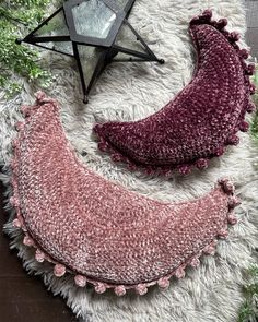 two pieces of knitted fabric sitting on top of a white rug next to a star