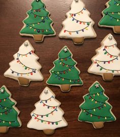 twelve decorated cookies with christmas trees and lights on them, all in different shapes and sizes