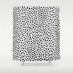 a shower curtain with black and white polka dots on the outside, in front of a gray background