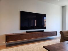 a flat screen tv mounted to the side of a wall in an empty living room