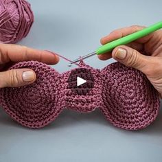 two hands are holding yarn and crocheting together to make a bow - shaped object