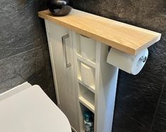 a white toilet sitting next to a wooden shelf with a plant on top of it