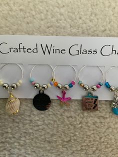 wine glass charms are hanging on a sign that says crafted wine glass charms