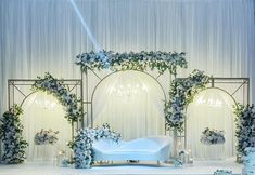 a white couch sitting on top of a stage covered in flowers and greenery next to candles