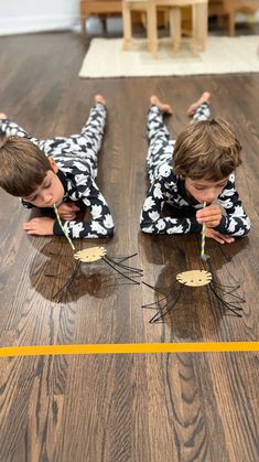 two young boys are playing on the floor with their toothbrushes and paper straws