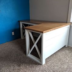 a white desk with a wooden top in front of a blue wall and carpeted floor