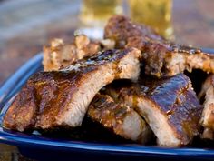 a blue plate topped with ribs covered in bbq sauce