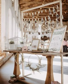 a wooden table topped with pictures and lights next to a white wall covered in string lights