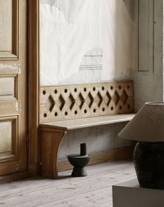 a wooden bench sitting in front of a window next to a lamp on a table